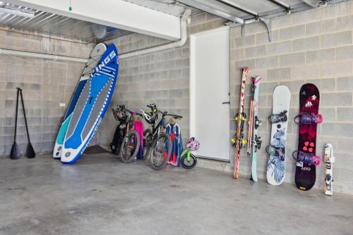 a bunch of snowboards and bicycles are lined up against a wall at Chilam C in Jindabyne