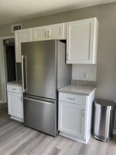 a kitchen with white cabinets and a stainless steel refrigerator at Gulf Coast Condos on the Sand Dunes - 101 in Dauphin Island