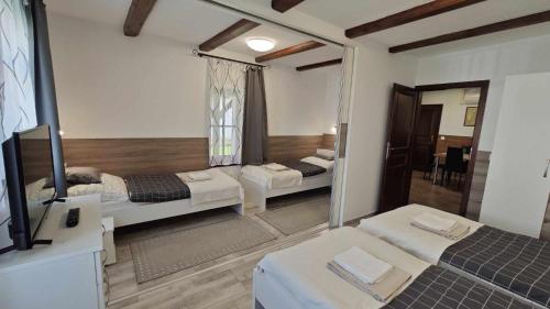 a room with two beds and a mirror at Három Grácia Vendégház in Rábapaty