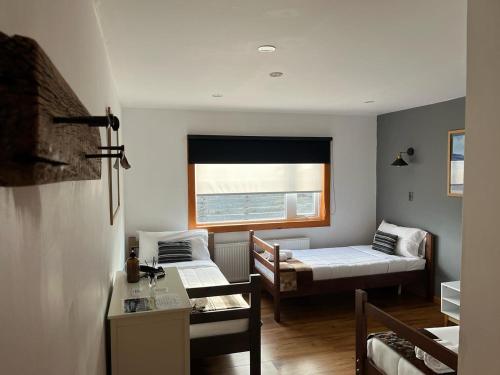 a small room with two beds and a window at Pristine Patagonia Hotel in Puerto Natales