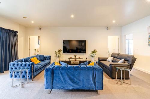 a living room with blue couches and a tv at Huge 4BR Pool Table & 75" TV in Ballarat