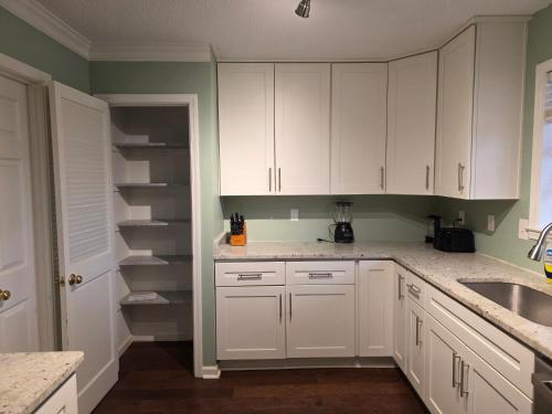 a kitchen with white cabinets and a sink at Modern Vast Southern Home with Pool Near Shops in Memphis