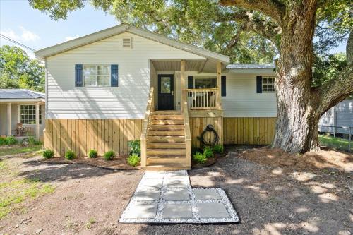 a house with a wooden door and a tree at Quaint Family Getaway on Biloxi in Dauphin Island