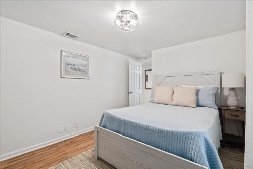 a white bedroom with a bed and a chandelier at Quaint Family Getaway on Biloxi in Dauphin Island