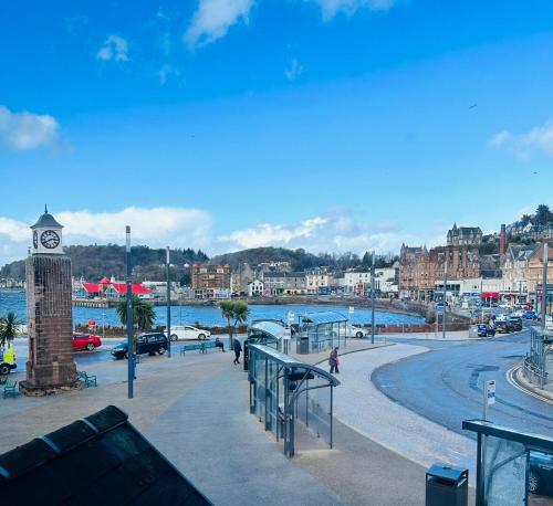 a clock tower in a town with a river and buildings at Kilmartin Court Apartments - No3 By The Sea & No2 With A View - free parking in Oban
