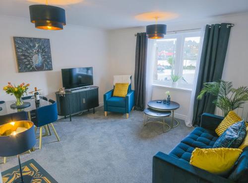 a living room with blue couches and a tv at Kilmartin Court Apartments - No3 By The Sea & No2 With A View - free parking in Oban