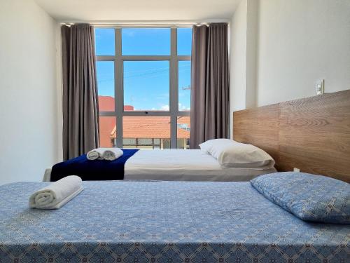 two beds in a hotel room with a window at Areias do Mar ! 2 Quartos, VistaMar + Varanda A205 in Barra de São Miguel