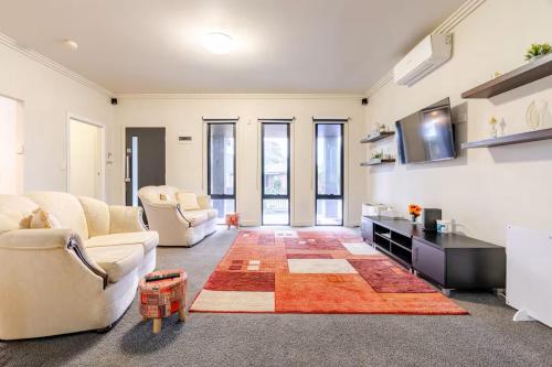 a living room with two couches and a tv at Huge 4BR Pool Table & 75" TV in Ballarat