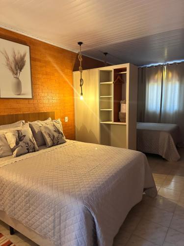 a bedroom with a white bed and a room with a sink at La vita hospedaria studio laranja in Nova Veneza