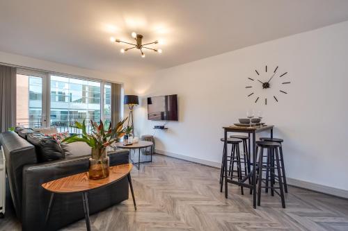 a living room with a couch and a clock on the wall at Stylish Belfast City Centre Apartment in Belfast