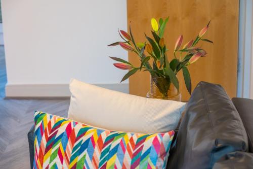 a vase of flowers sitting next to two pillows at Stylish Belfast City Centre Apartment in Belfast