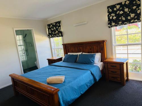 Un dormitorio con una cama con edredón azul y dos ventanas. en Seaside Luxury 4bedroom House, en Auckland