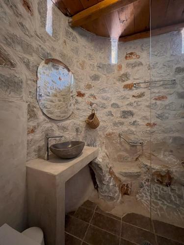 a stone bathroom with a sink and a mirror at Achelatis Traditional Guest Houses in Areopolis