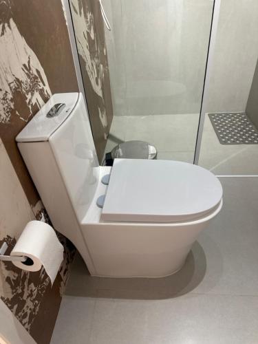 a white toilet in a bathroom with a shower at La vita hospedaria studio laranja in Nova Veneza