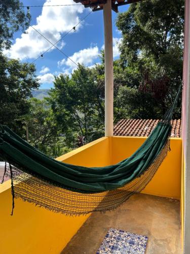 a hammock on the porch of a yellow house at Pousada Flor da Mata in Nova Lima