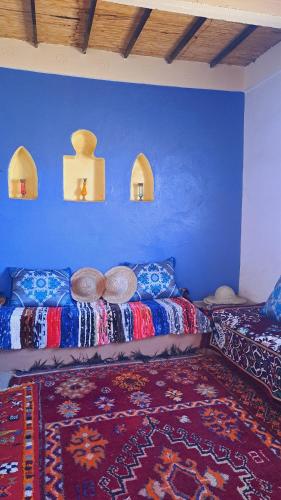 a room with two beds and a blue wall at LA PETITE MAISON DU LAC IRIKI in Foum Zguid
