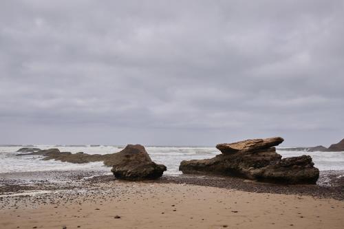 a beach with some rocks in the water at Amwaj Apt - Golden Sands and Blue Waves Beach Escape in Mirleft