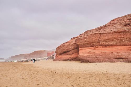 a group of people standing on a beach next to a cliff at Amwaj Apt - Golden Sands and Blue Waves Beach Escape in Mirleft
