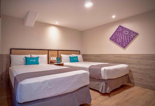 a hotel room with two beds with blue pillows at Continental Mexicano in Mexico City