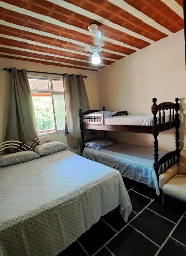 a bedroom with two beds and a ceiling with beams at Casa Costa Verde-Muriqui in Vila Muriqui