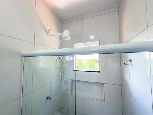 a bathroom with a glass shower with a window at Apartamento 5 Duplex 2 Suites Perto Praia do Mutá in Santa Cruz Cabrália
