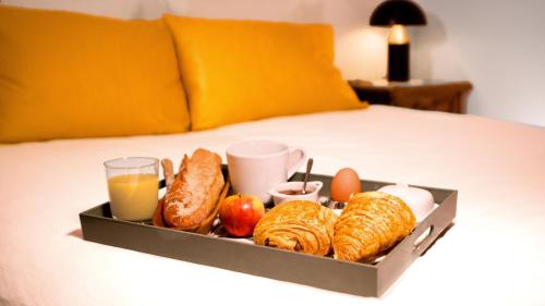- un plateau de croissants et d'autres aliments pour le petit-déjeuner sur le lit dans l'établissement Le 20 - Garden suite, à Fontenay-sous-Bois