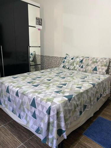 a bedroom with a bed with a quilt on it at La Melangerie - Hostel in Bertioga