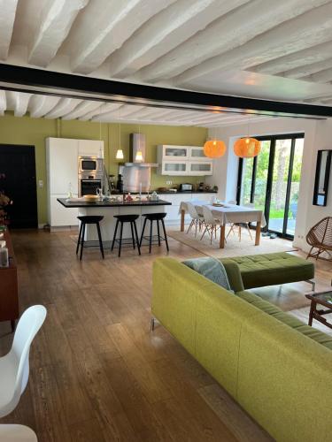 un salon avec un canapé vert et une cuisine dans l'établissement Maison de charme dans le vieux Marly, à Marly-le-Roi