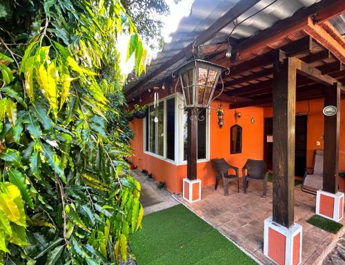 an orange house with a porch and a table and chairs at El encanto tropical, a minutos del IRTRA in Ajaxá