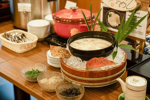 a table with a pot of soup and bowls of food at KAMENOI HOTEL Kochi in Ino