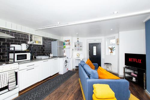 a living room with a blue couch in a kitchen at Exclusive Apartment - close to centre, contactless entry, free parking, WiFi & Netflix in Leeds