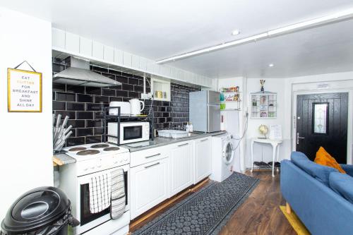 a kitchen with white cabinets and a blue couch at Exclusive Apartment - close to centre, contactless entry, free parking, WiFi & Netflix in Leeds