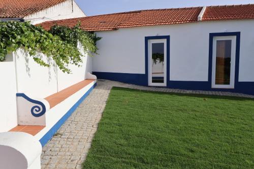 a white and blue house with a green yard at Herdade do Vidigal in Montemor-o-Novo