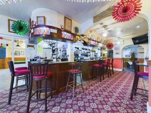 a bar in a restaurant with pink chairs at Northcote Hotel in Bridlington