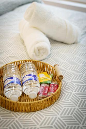 - un panier de boissons et d'articles de toilette sur un lit dans l'établissement Le petit joyau de Voltaire, à Saint-Quentin