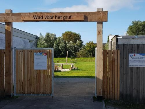 a wooden gate with a sign that reads wait your hot quit at Cabin in Tzummarum with Pool and Tennis Court in Tzummarum
