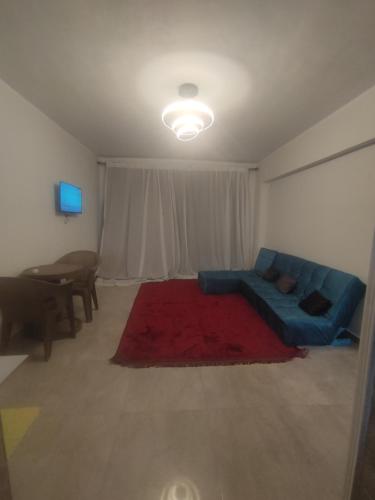 a living room with a blue couch and a red rug at شقة فندقية قريبة من المتحف المصرى ومول مصر والاهرامات عجائب الدنيا السبعة in Cairo