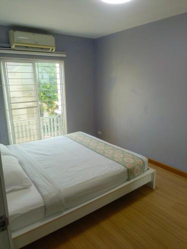 a bed in a room with a large window at Private Room in a Shared Homestay in Thalang