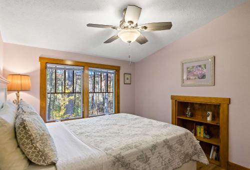 a bedroom with a bed with a ceiling fan and a window at Snug Cabin with Hiking Trail and Private Lake Access in Grand Junction