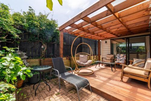 a patio with a wooden pergola with chairs and a table at Auckland Golden Phoenix Holiday Homes in Auckland