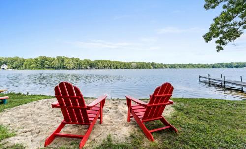 two red chairs sitting on the sand near a lake at Lakefront Retreat in a Serene Country Setting in Pullman