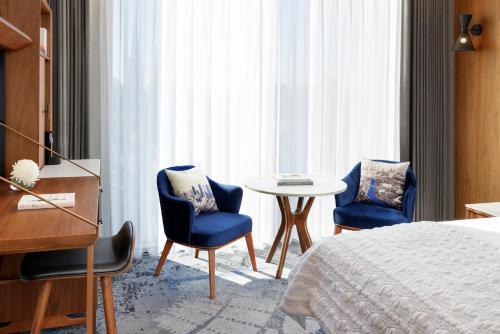 a hotel room with a bed and two chairs and a table at Le Meridien Melbourne in Melbourne