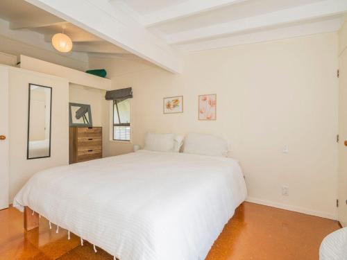 a white bedroom with a large white bed at Hosts on the Coast Cooks Crib in Cooks Beach