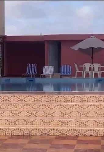 a swimming pool with chairs and an umbrella at Charmante villa à Safi in Safi