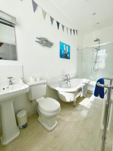 a bathroom with a toilet and a bath tub and a sink at Lyme Regis renovated period seaside flat in Lyme Regis