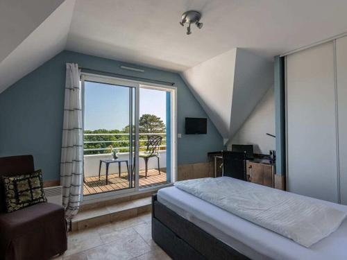 a bedroom with a bed and a view of a balcony at DUXCAAR Saint Pabu Comfortable holiday residence in Saint-Pabu
