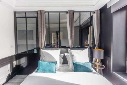une chambre avec un grand lit blanc avec des oreillers bleus dans l'établissement Modern apartment - 1BR 4P - Plaine-Monceau, à Paris