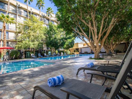 a swimming pool with chaise lounges next to a hotel at Hotel Araiza Mexicali in Mexicali