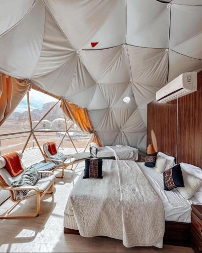 1 camera da letto in una tenda con letto e sedie di RUM CAMILLA lUXURY CAMP a Wadi Rum