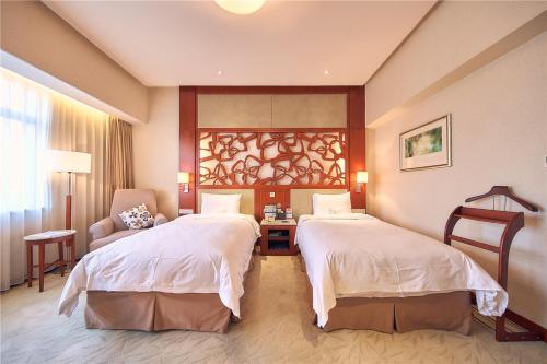 a hotel room with two beds and a chair at Parkview Hotel in Shanghai